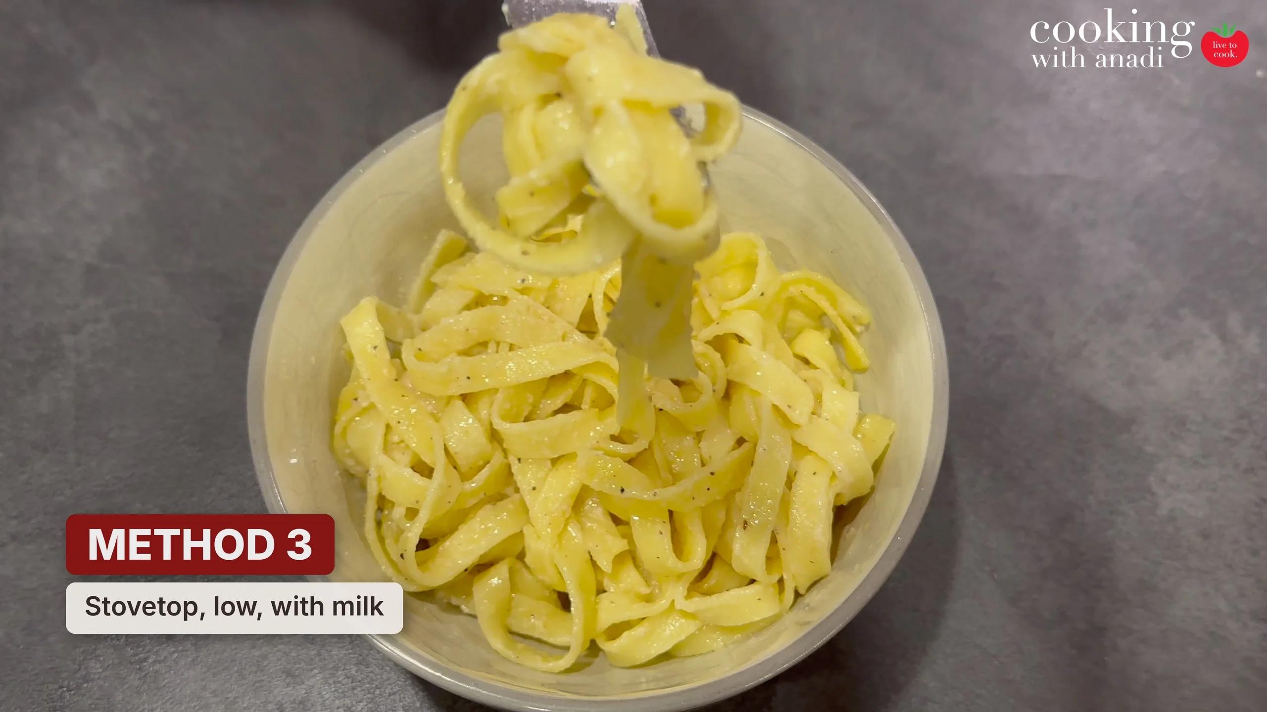 Leftover fettuccine alfredo reheated in a pan on low heat with milk, the strands loose and coated