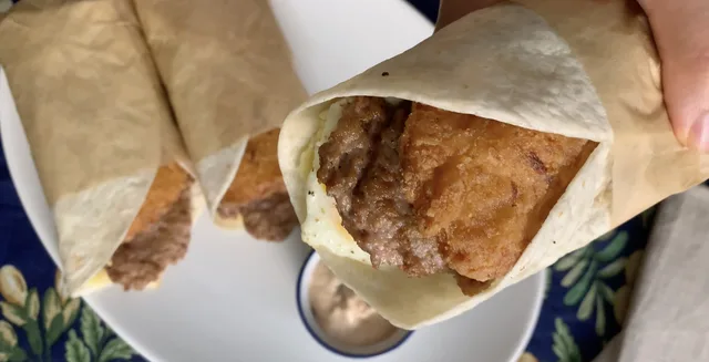 Tim Hortons Farmer's Wrap unwrapped in parchment paper, showing cooked meat filling inside a flatbread.