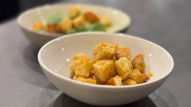 Golden crispy homemade croutons in white bowls served as a garnish for soups and salads.