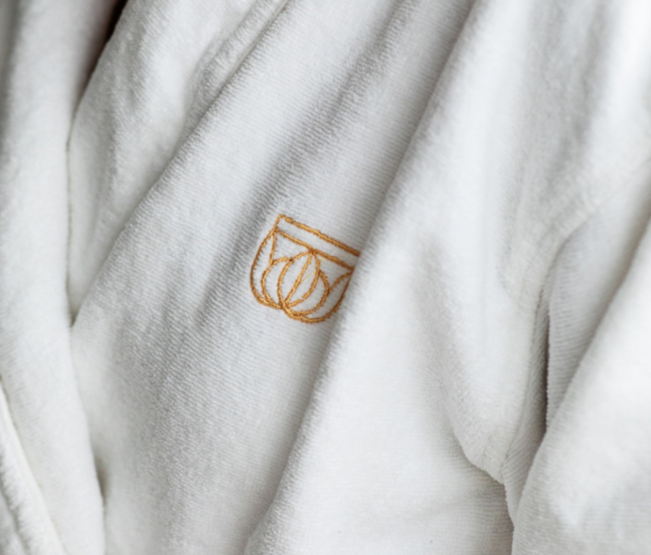 Embroidered Britannia Hotel symbol on a white bathrobe