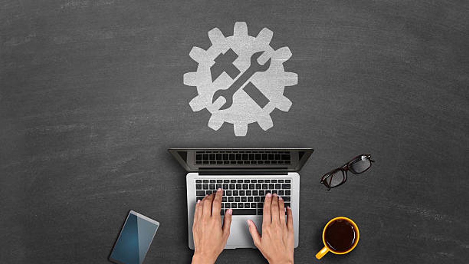 Hands typing on laptop with tools icon.