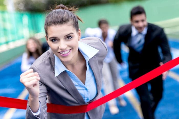 Businesswoman crossing finish line in race