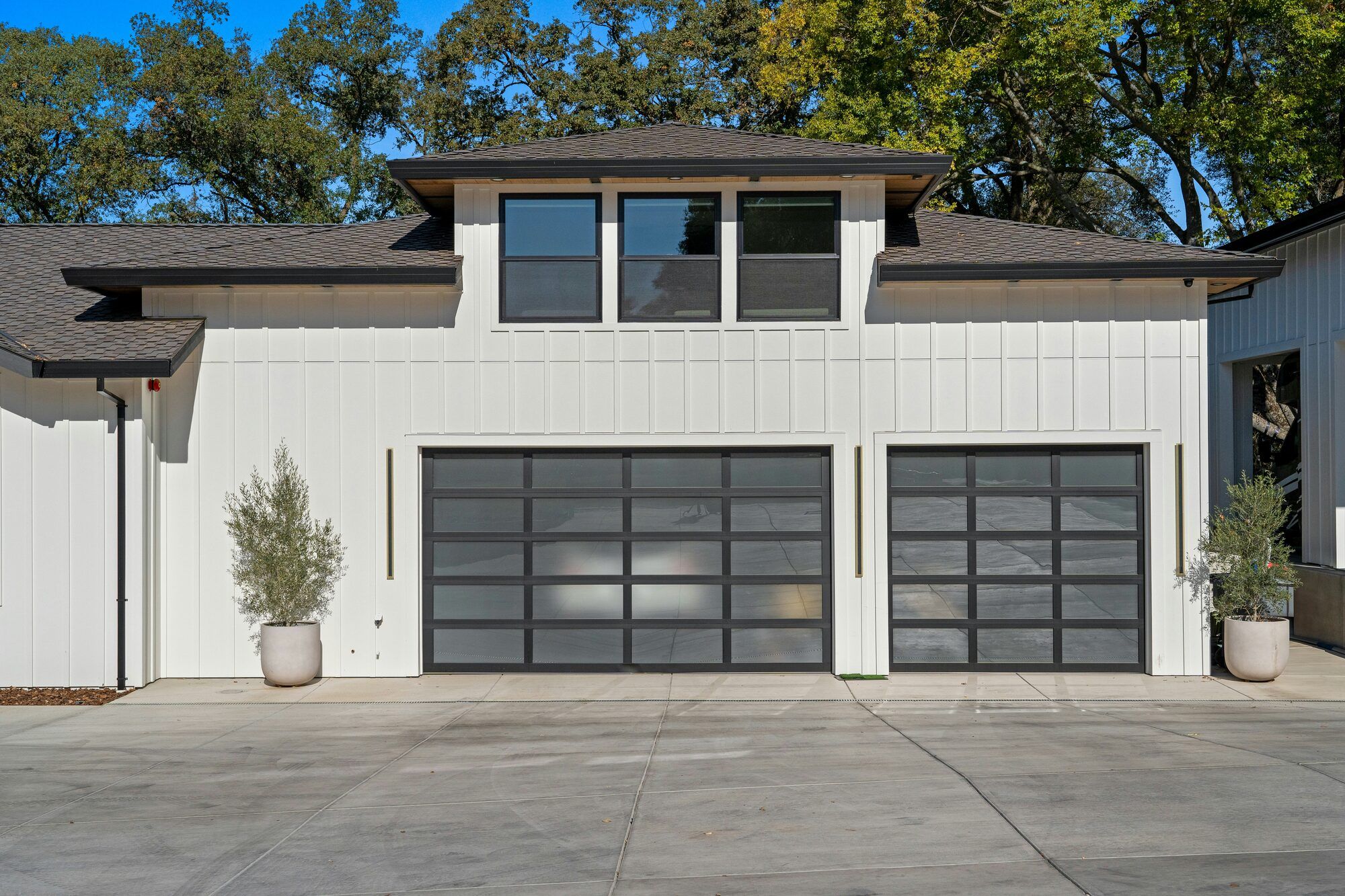 A white two-story home with two modern glass-panel garage doors