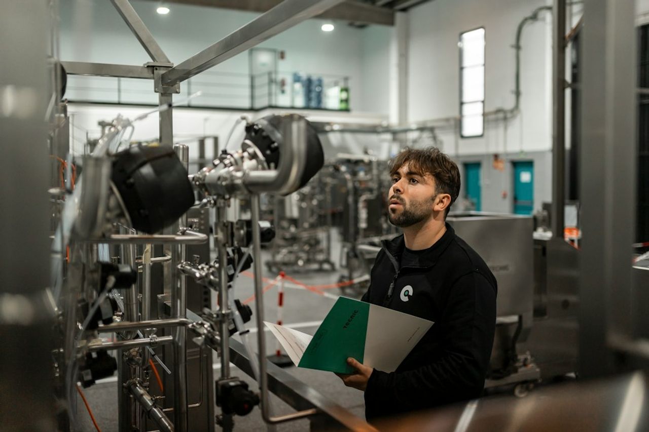 A technician reviewing an industrial piping installation with technical documents in hand.