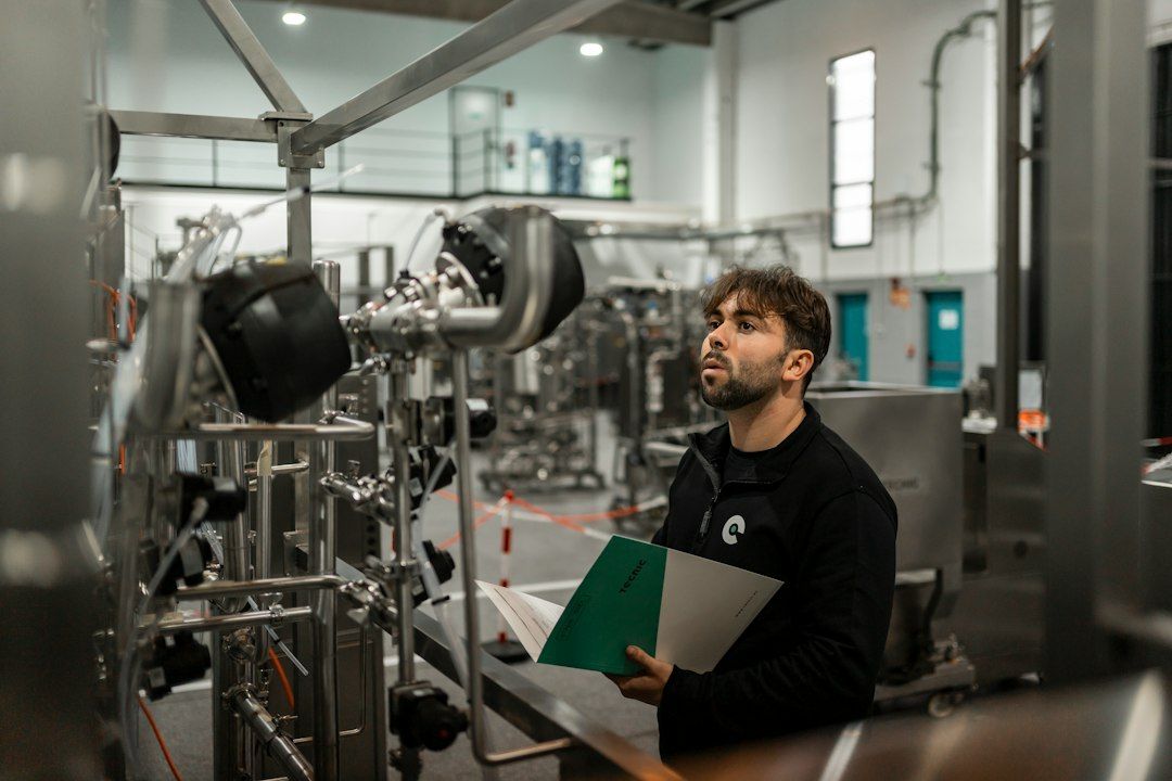 A technician reviewing an industrial piping installation with technical documents in hand.