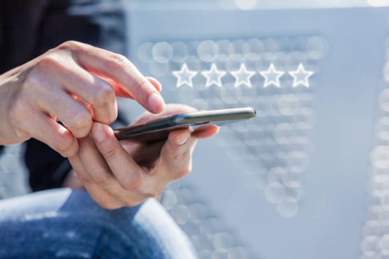 Person using smartphone with five-star review icons