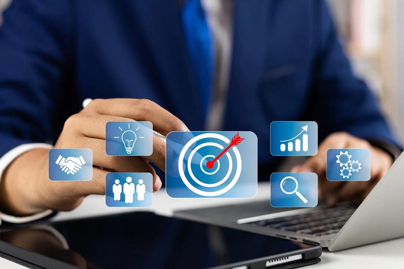 A person in a suit touches a virtual icon of a target with an arrow, symbolizing a goal. Other icons, representing Product Market Development (PMD), include a handshake, lightbulb, group of people, bar chart, and magnifying glass—denoting ideas, teamwork, success metrics, and search/research.