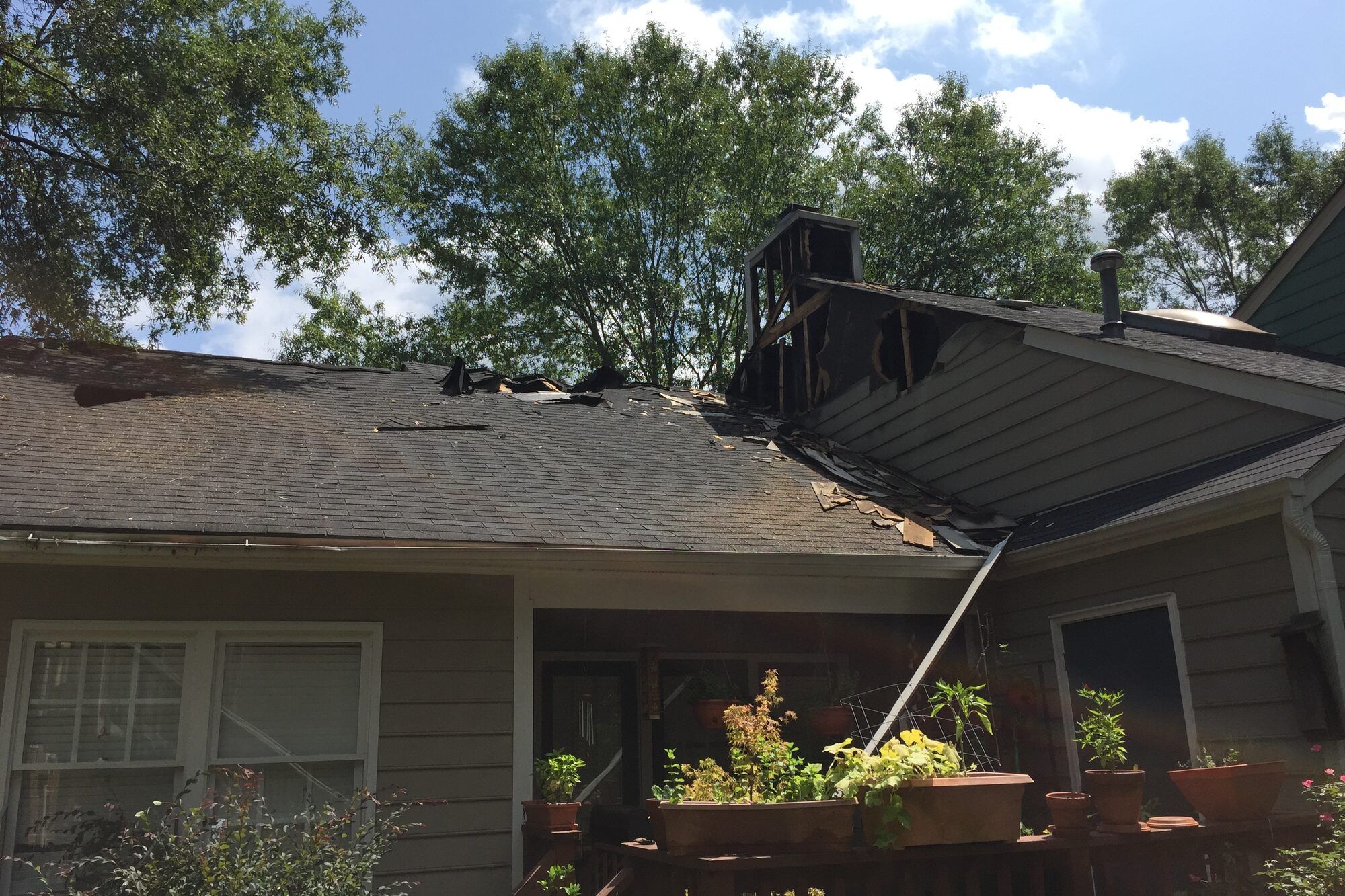 Fire and storm damage to the roof of a single-storey house before restoration work