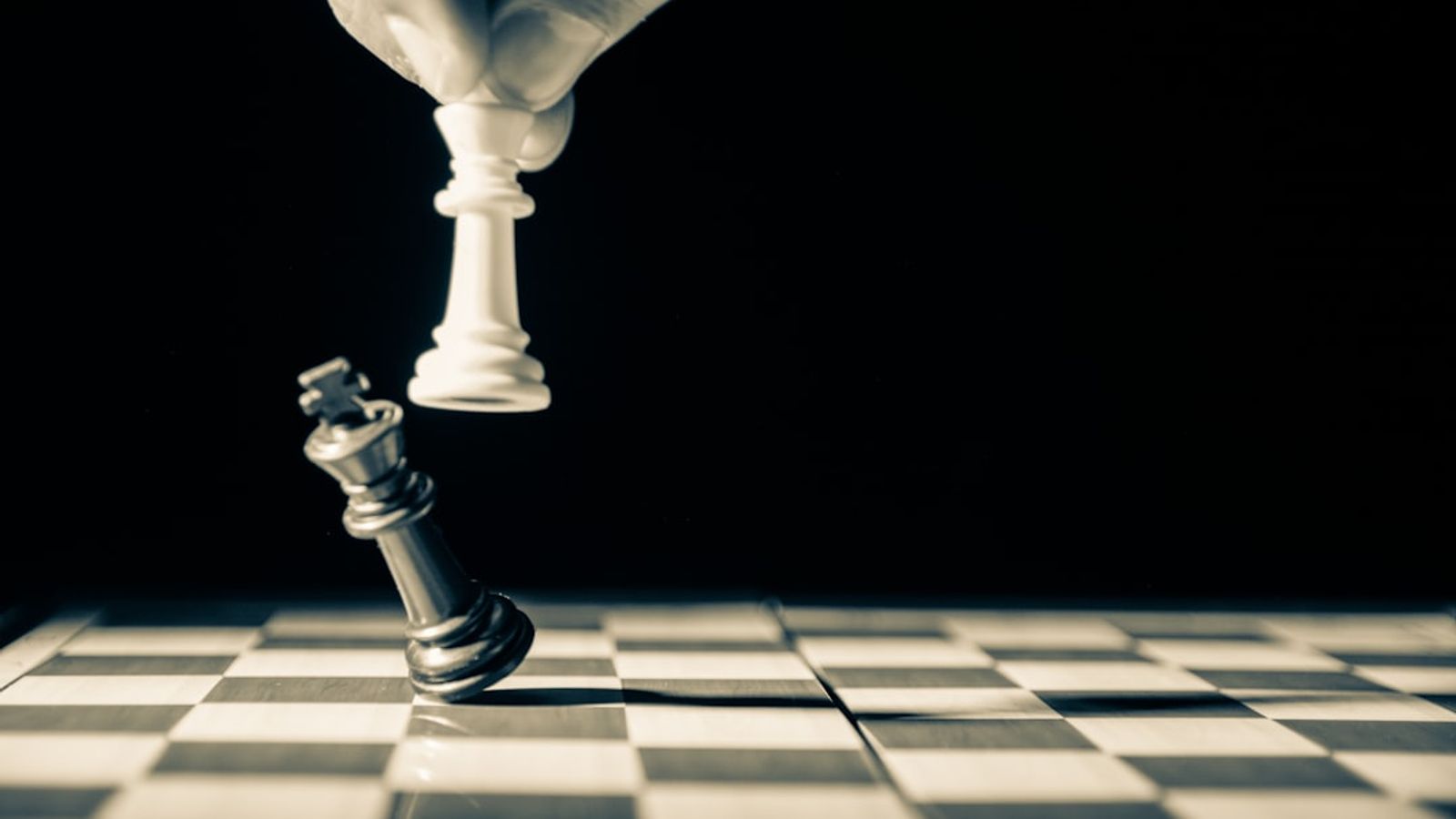 A white chess king toppling a black king — finding the one weakness you can attack