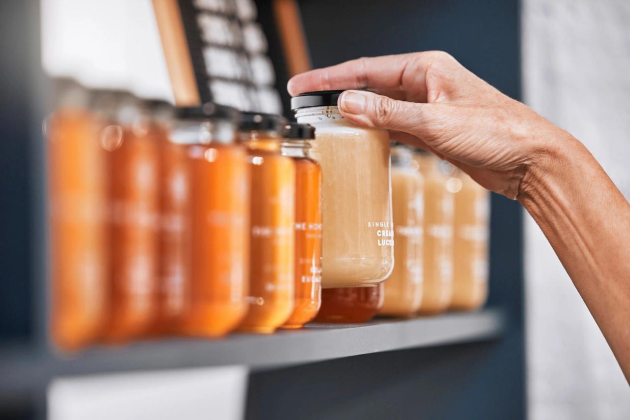 Hand selecting jar of honey on shelf