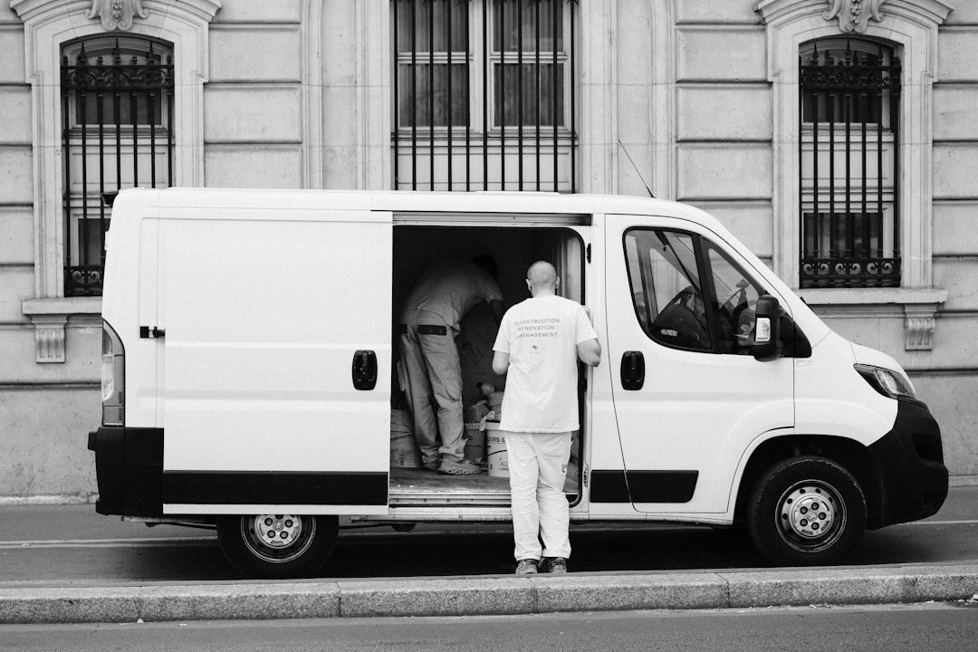 A tradesperson unloading supplies from the side door of a white work van.