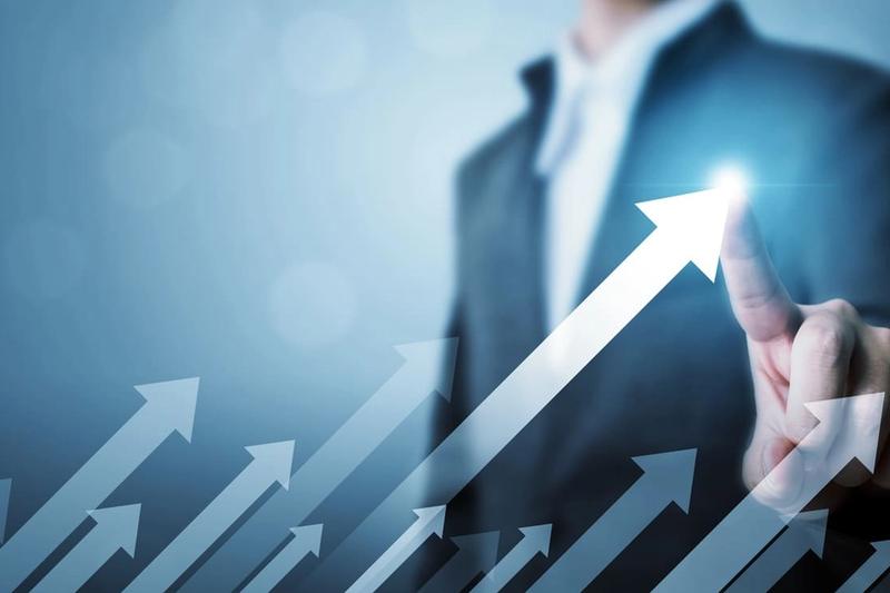 A businessman in a suit touching the tip of a rising arrow, with more arrows curving upward behind it.