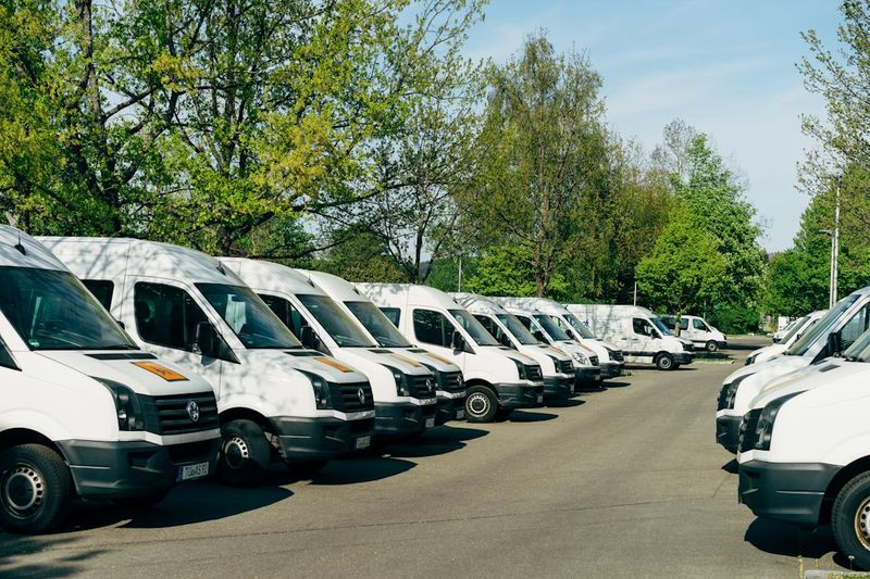A row of white service vans parked side by side in a lot.