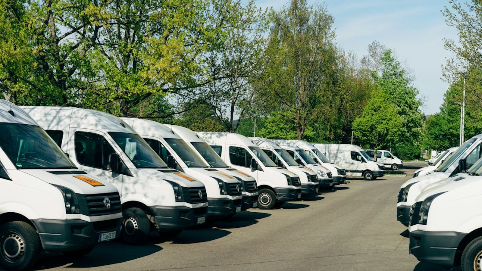 A row of white service vans parked side by side in a lot.