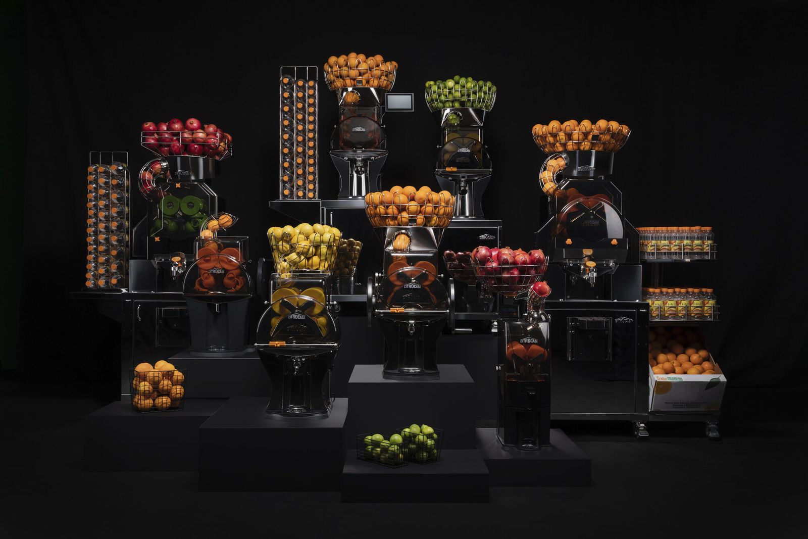 The Citrus America range of commercial juicing machines, arranged with baskets of oranges, apples and limes