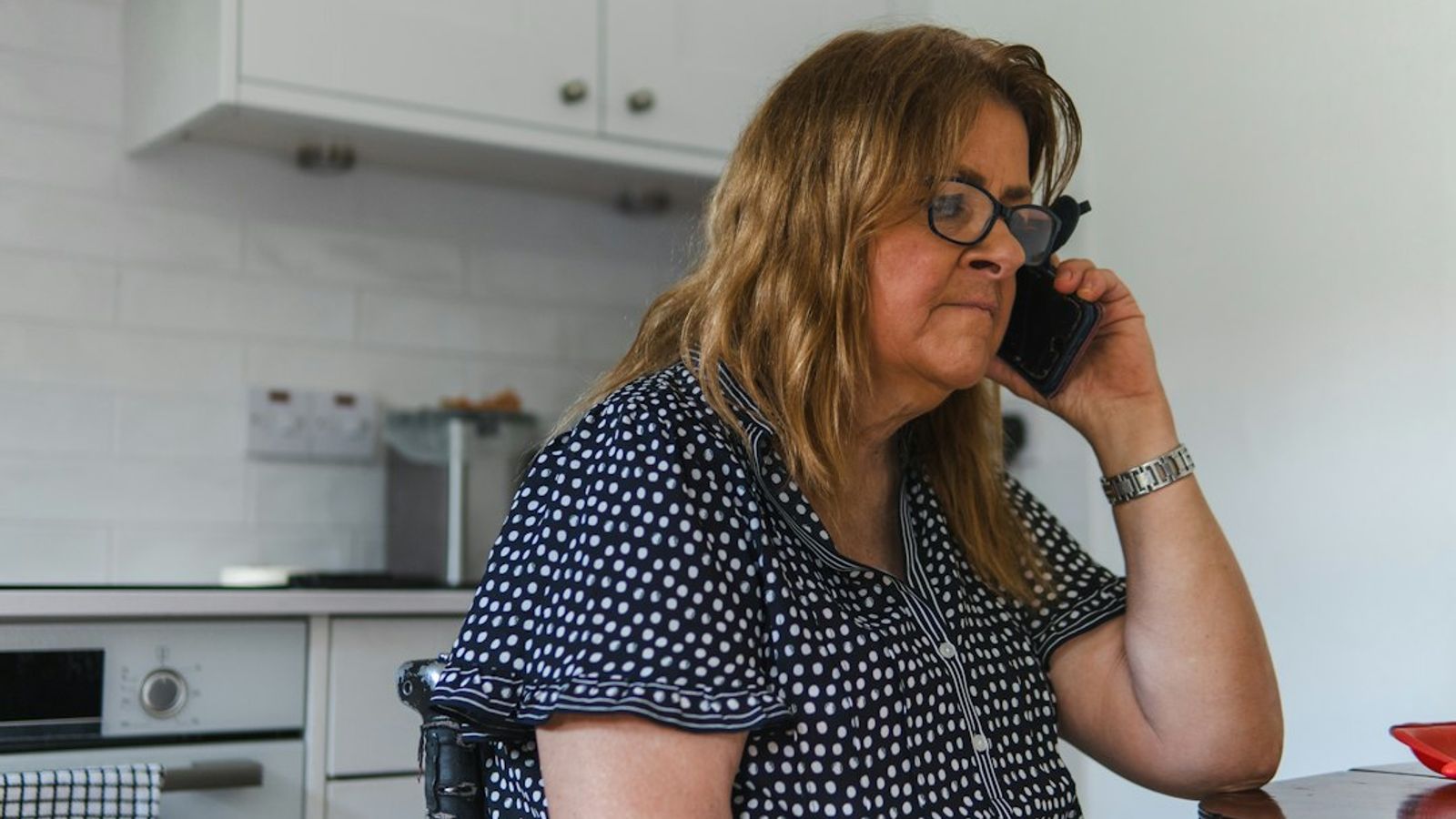 A woman talking on a mobile phone in her kitchen.