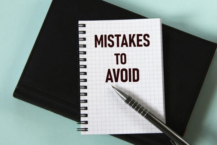 Notebook with 'MISTAKES TO AVOID' text and a pen