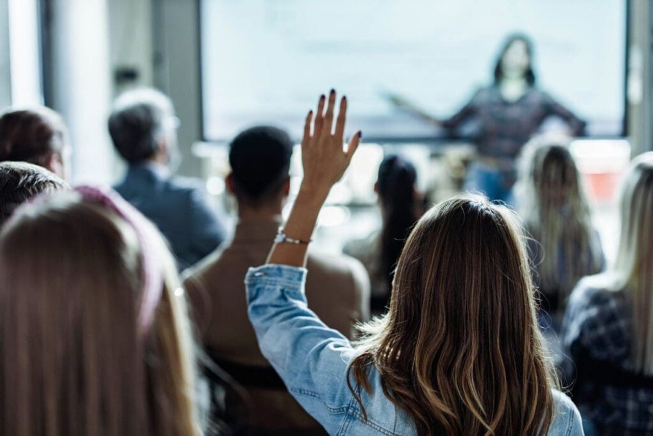 Audience member raising hand at a business seminar