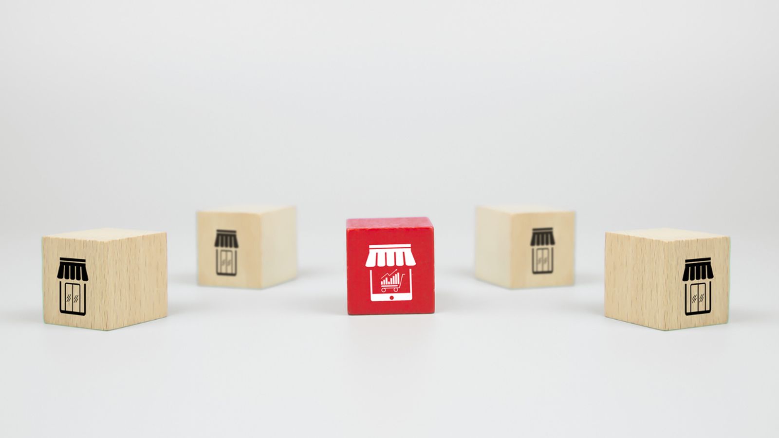 Wooden blocks with store icons, one red online.