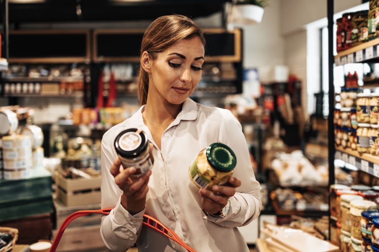 Woman comparing grocery items in a store.