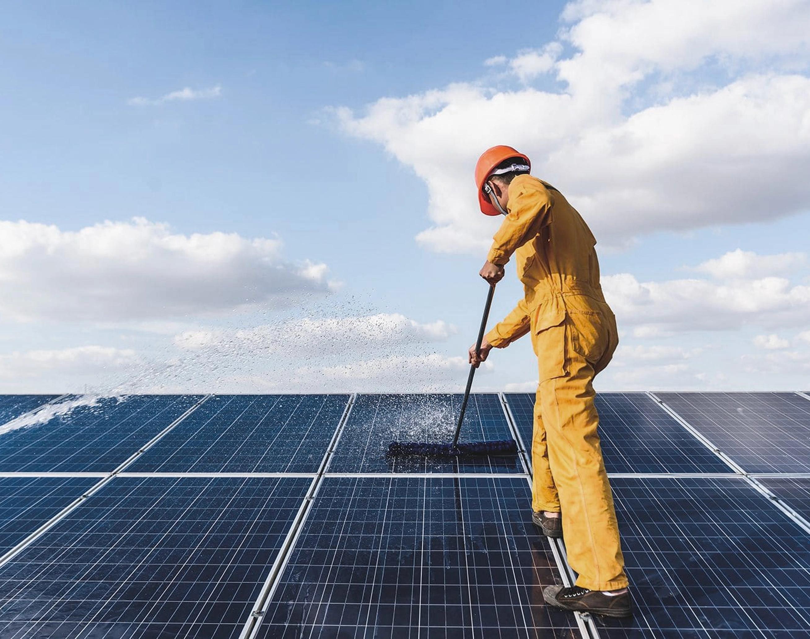 una persona che pulisce dei pannelli fotovoltaici