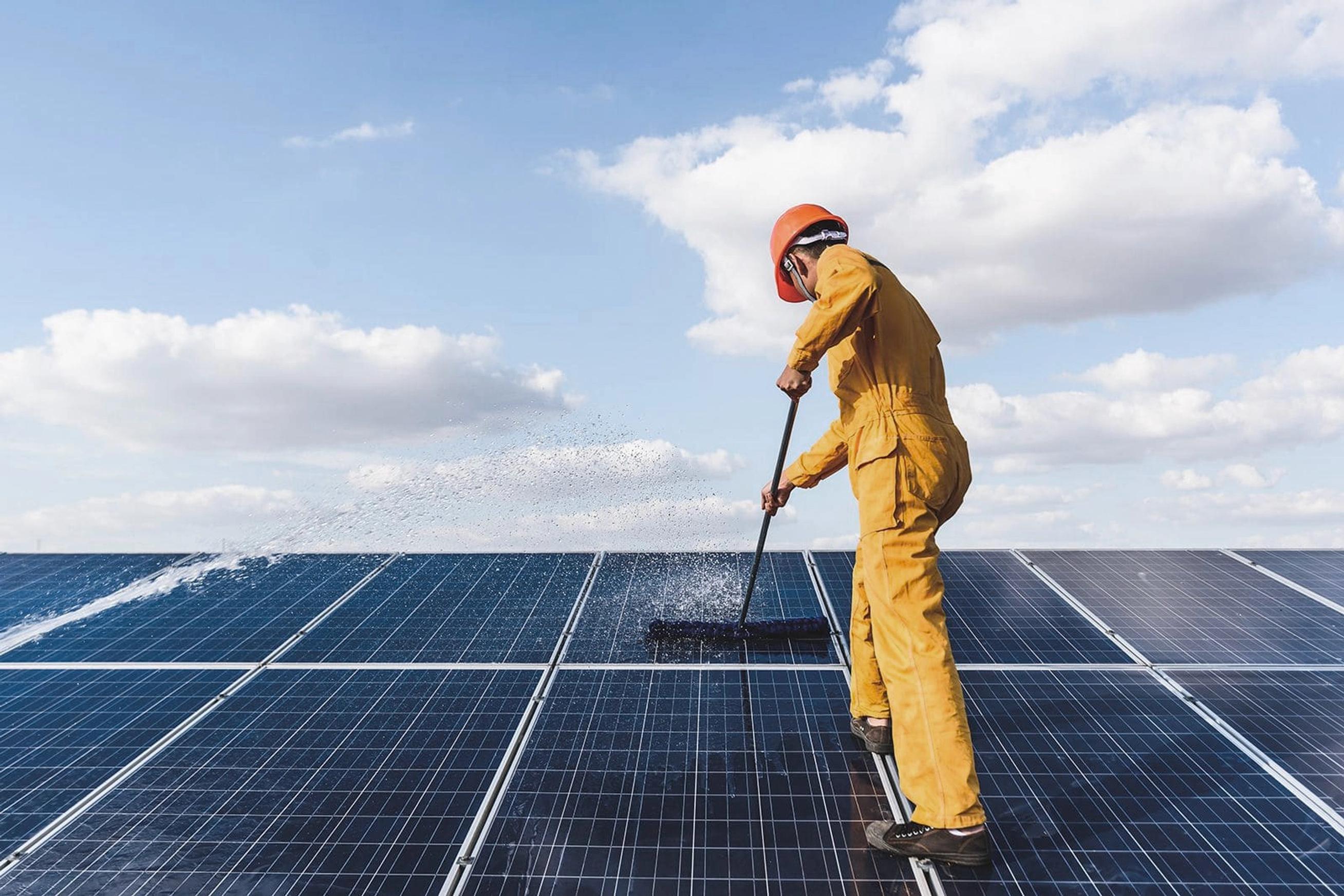 una persona che pulisce dei pannelli fotovoltaici