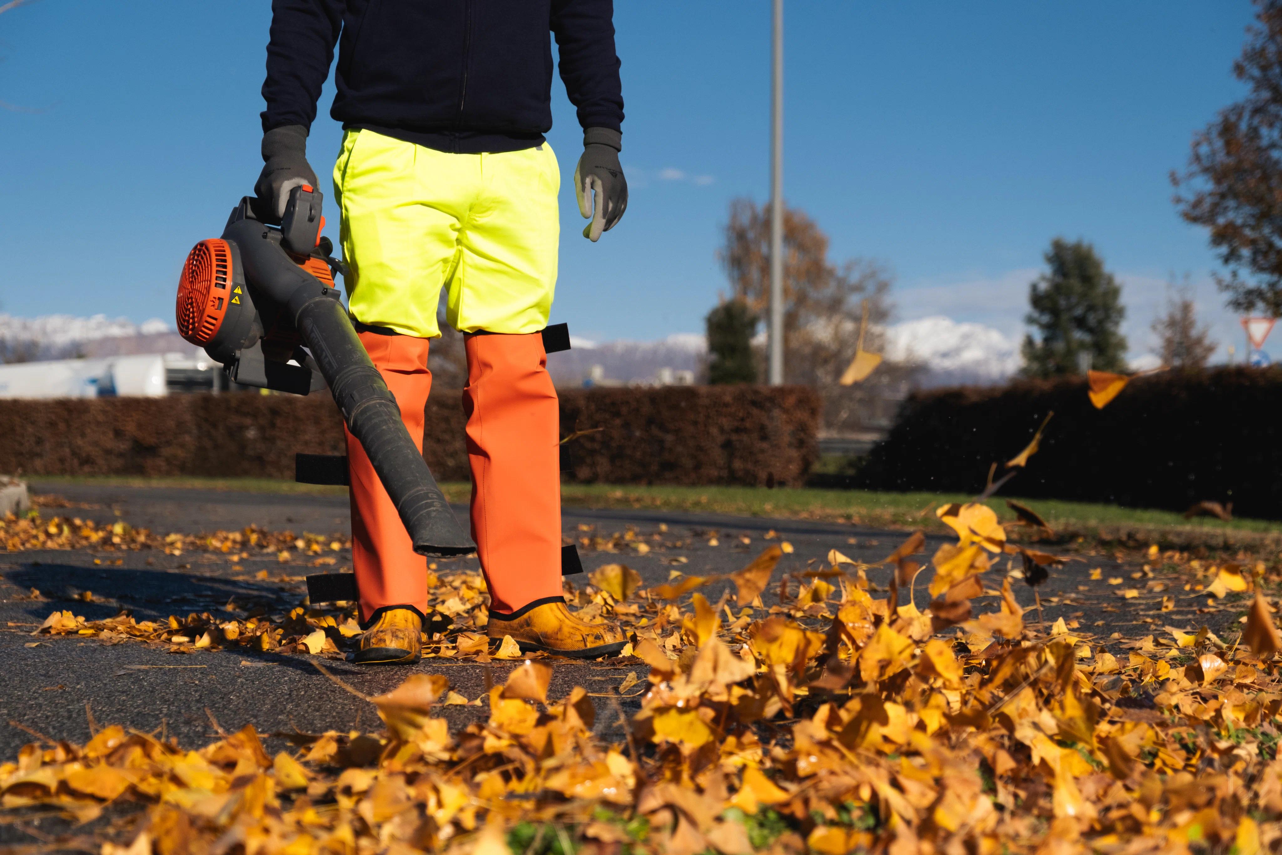 una persona che pulisce la strada dalle foglie