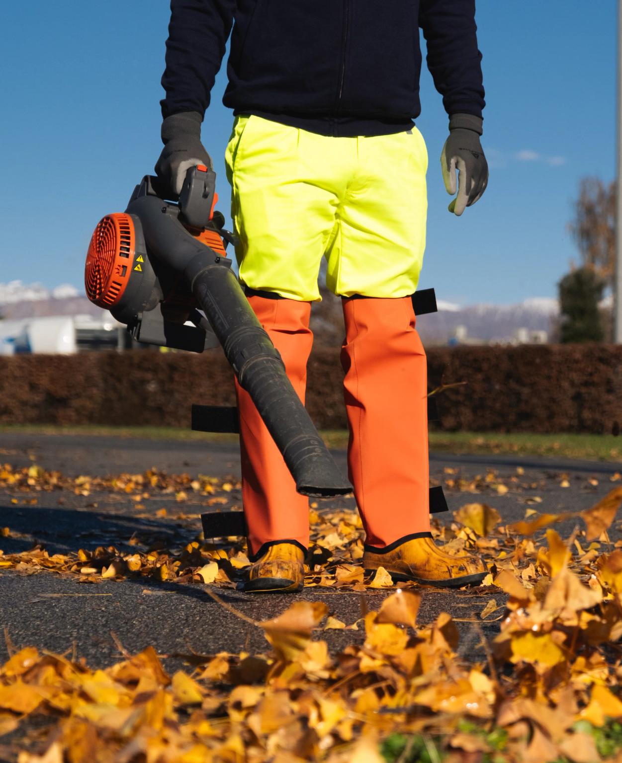 una persona che pulisce la strada dalle foglie