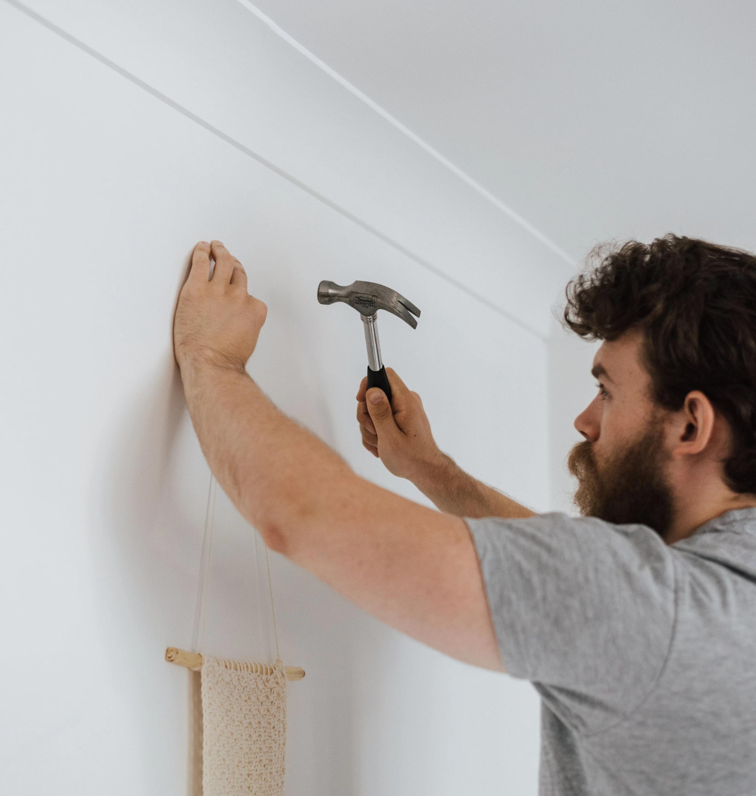 una persona che fissa un chiodo al muro con un martello