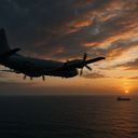 Aircraft flying over the ocean at sunset