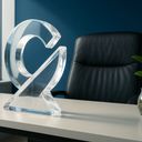 Clear abstract sculpture on a desk with a plant