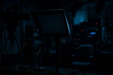 Dimly lit studio with a monitor and microphones