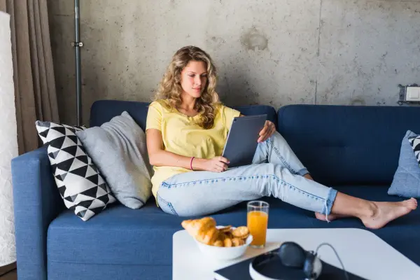 Mujer navegando con una tablet conectada al WiFi desde el sofá de casa
