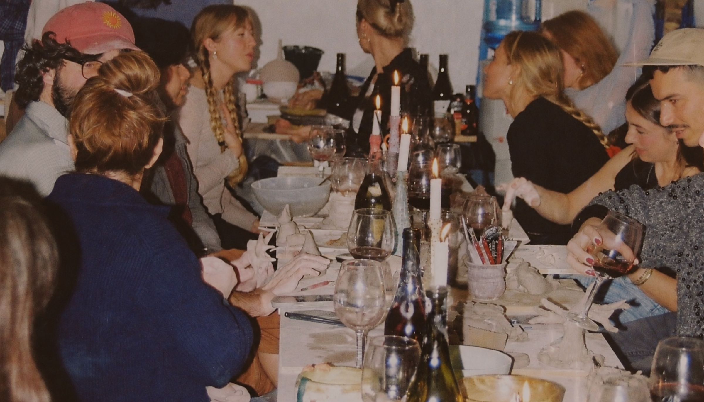 Gjester rundt et langbord i Dreie-studioet med leire, stearinlys og vin