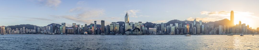 Panoramic view of a city skyline at sunset over water.