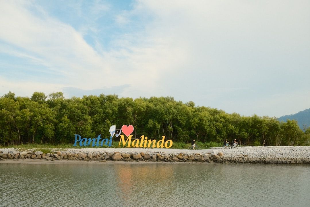 Pantai malindo sign near water and trees.