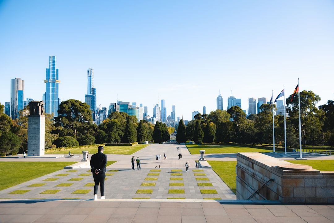 Man stands on steps overlooking city skyline and park