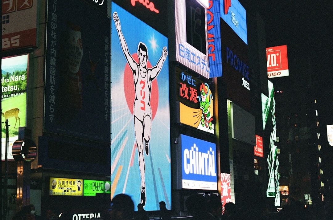 Neon signs illuminate a city street at night.