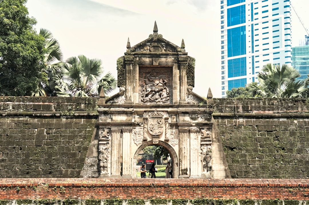 A stone gate with a clock tower in the background