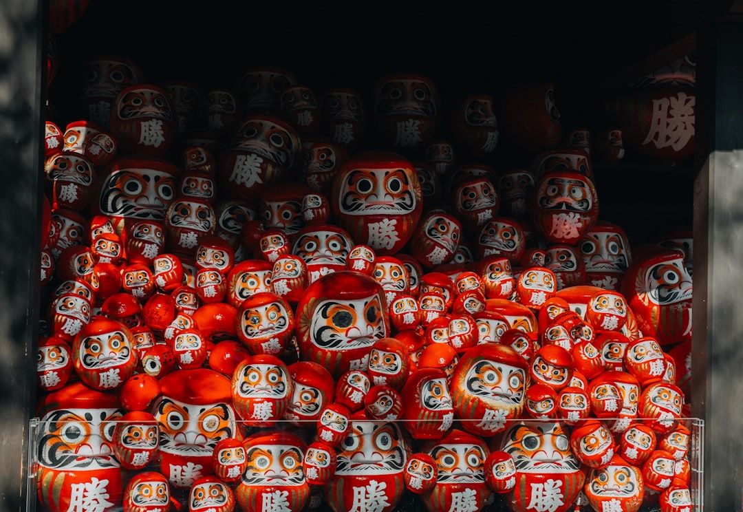 A collection of red and white daruma dolls.