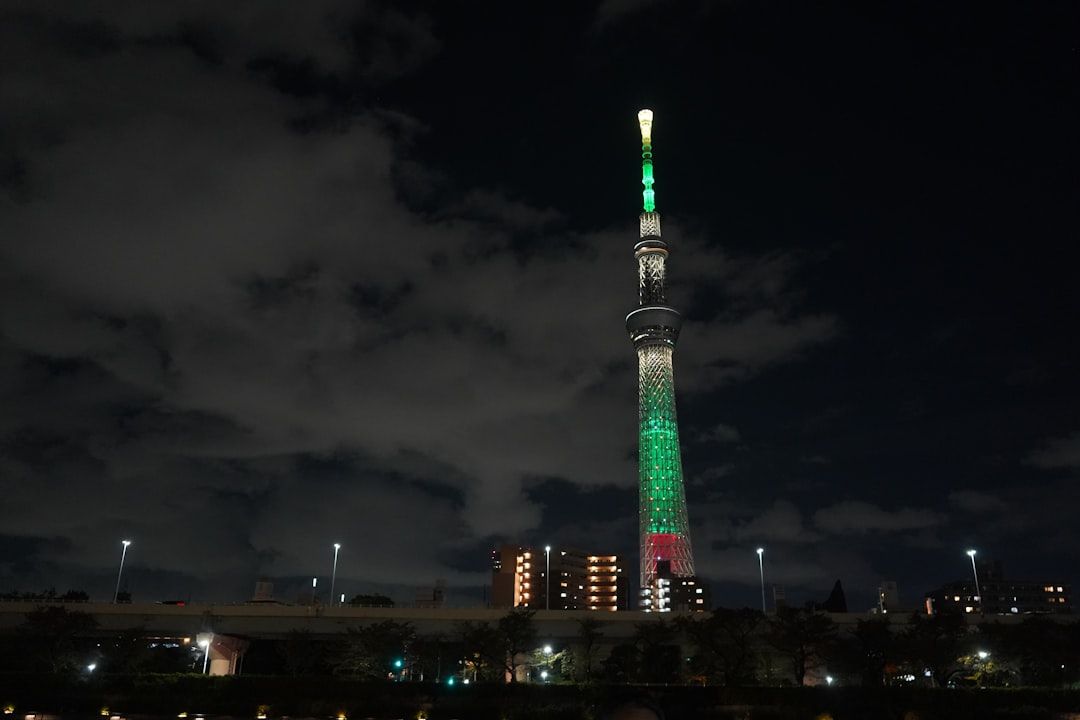 Tall illuminated tower at night with green lights