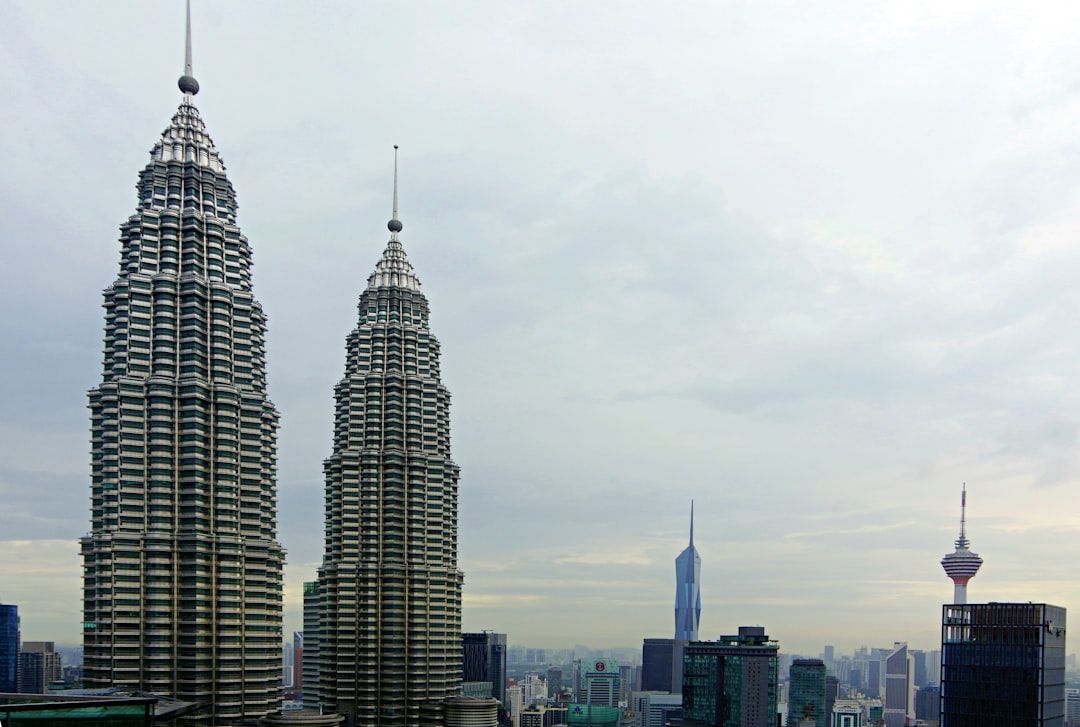 Two modern skyscrapers against a cloudy sky.