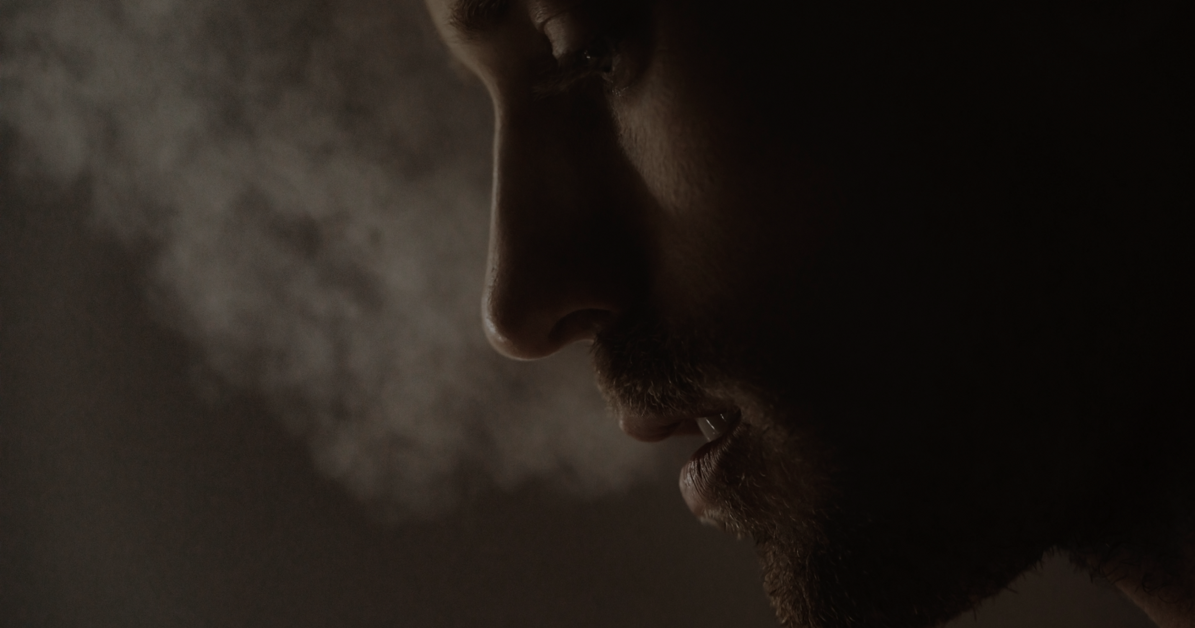 Close up of a man's face from the side as steam flows from his mouth