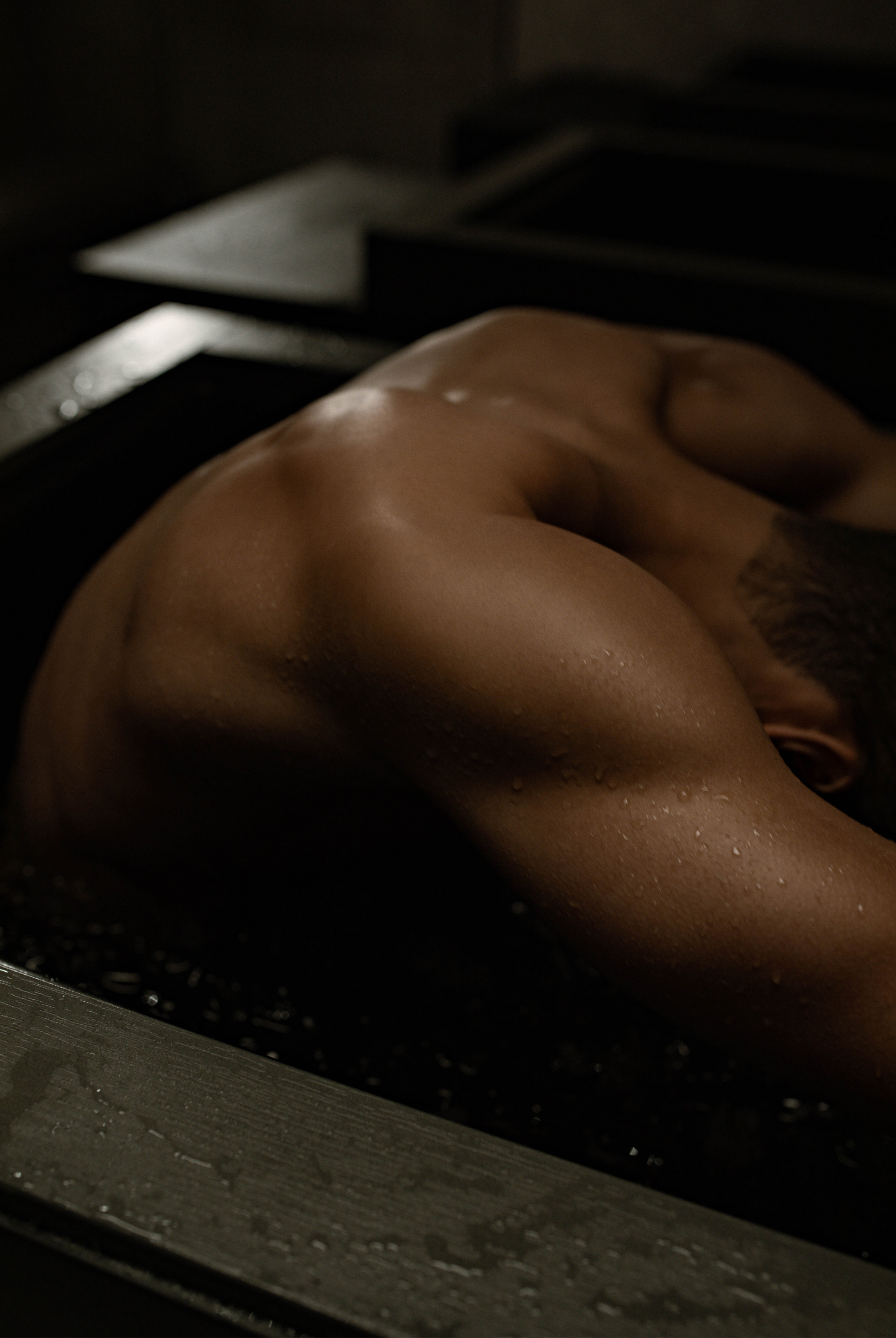 A man hunches over while sitting in an ice bath