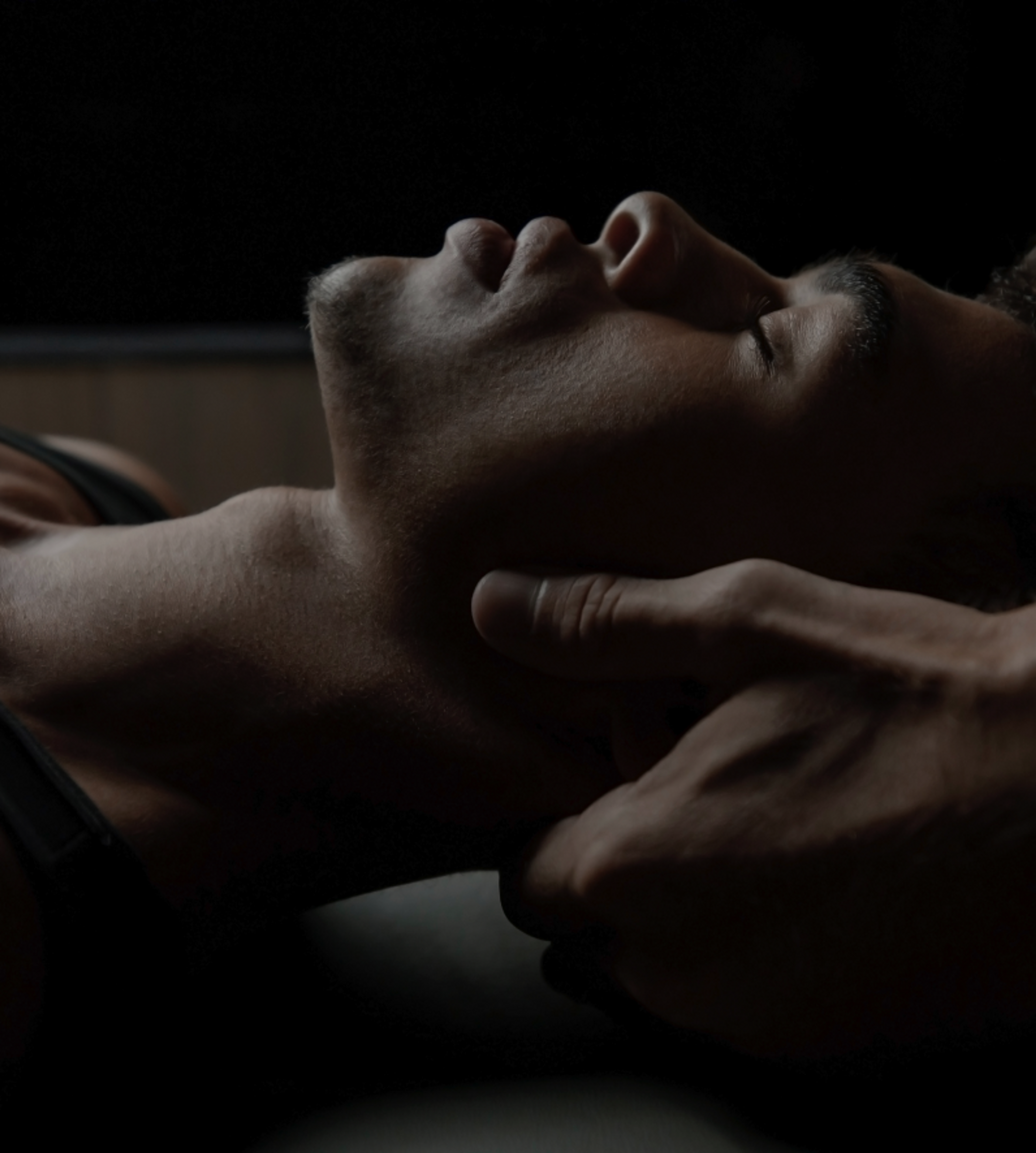 Close up of hands holding a man's head from behind while he lays on a table