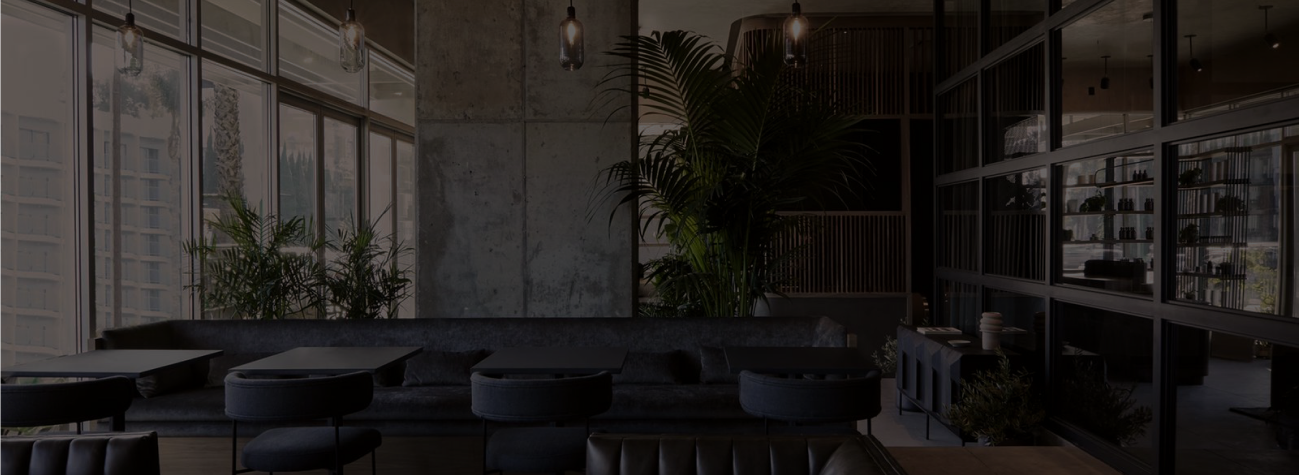 A row of chairs and a booth of two person tables and plants in the back