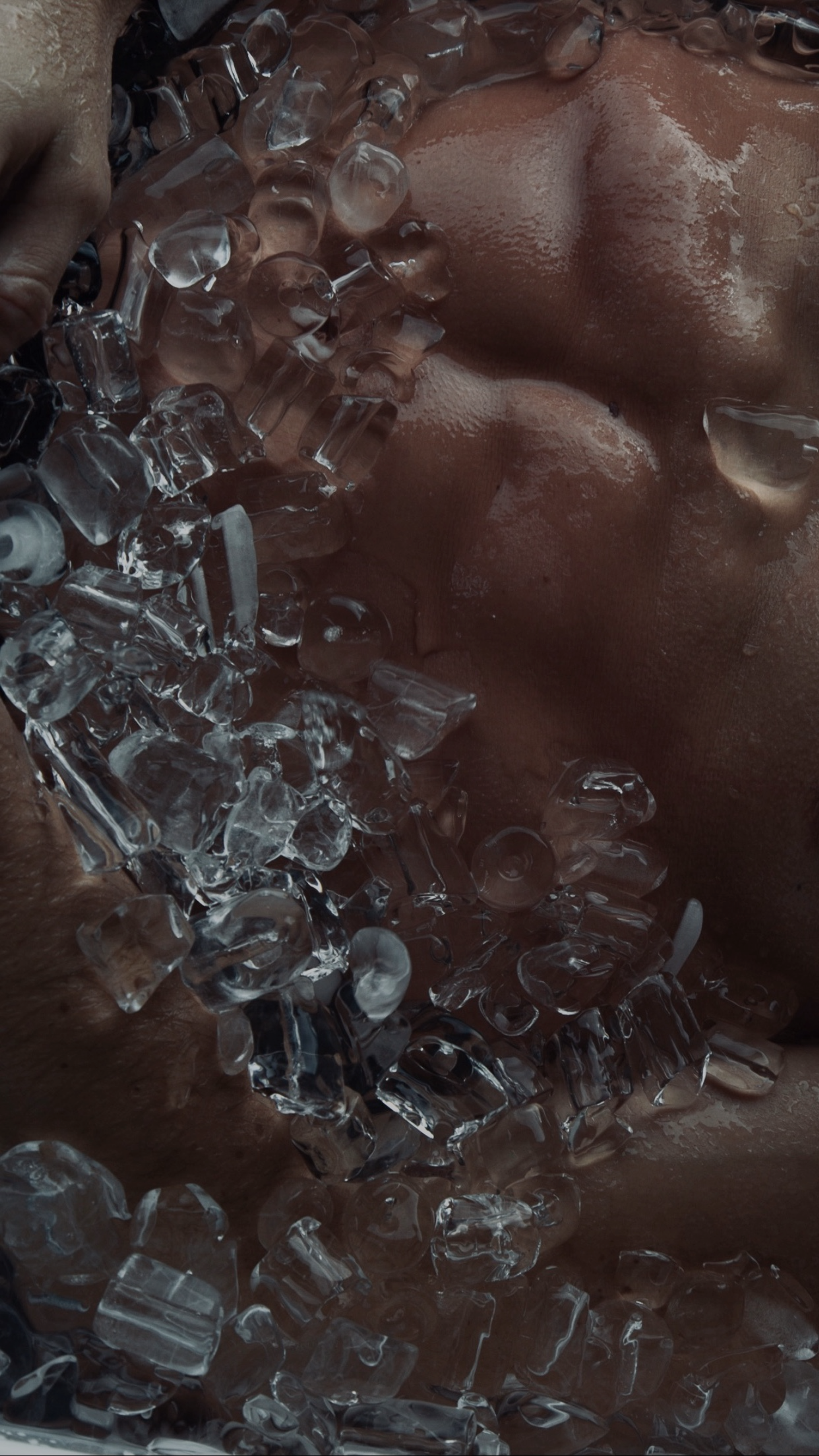 Close up of a man's abdomen surrounded by ice water