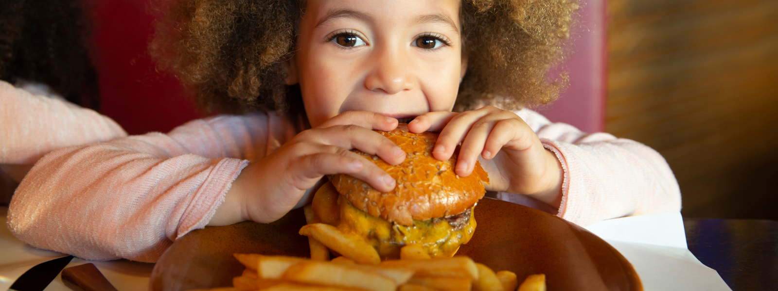 child eating burger and fries