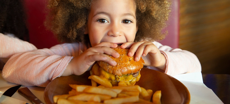 child eating burger and fries