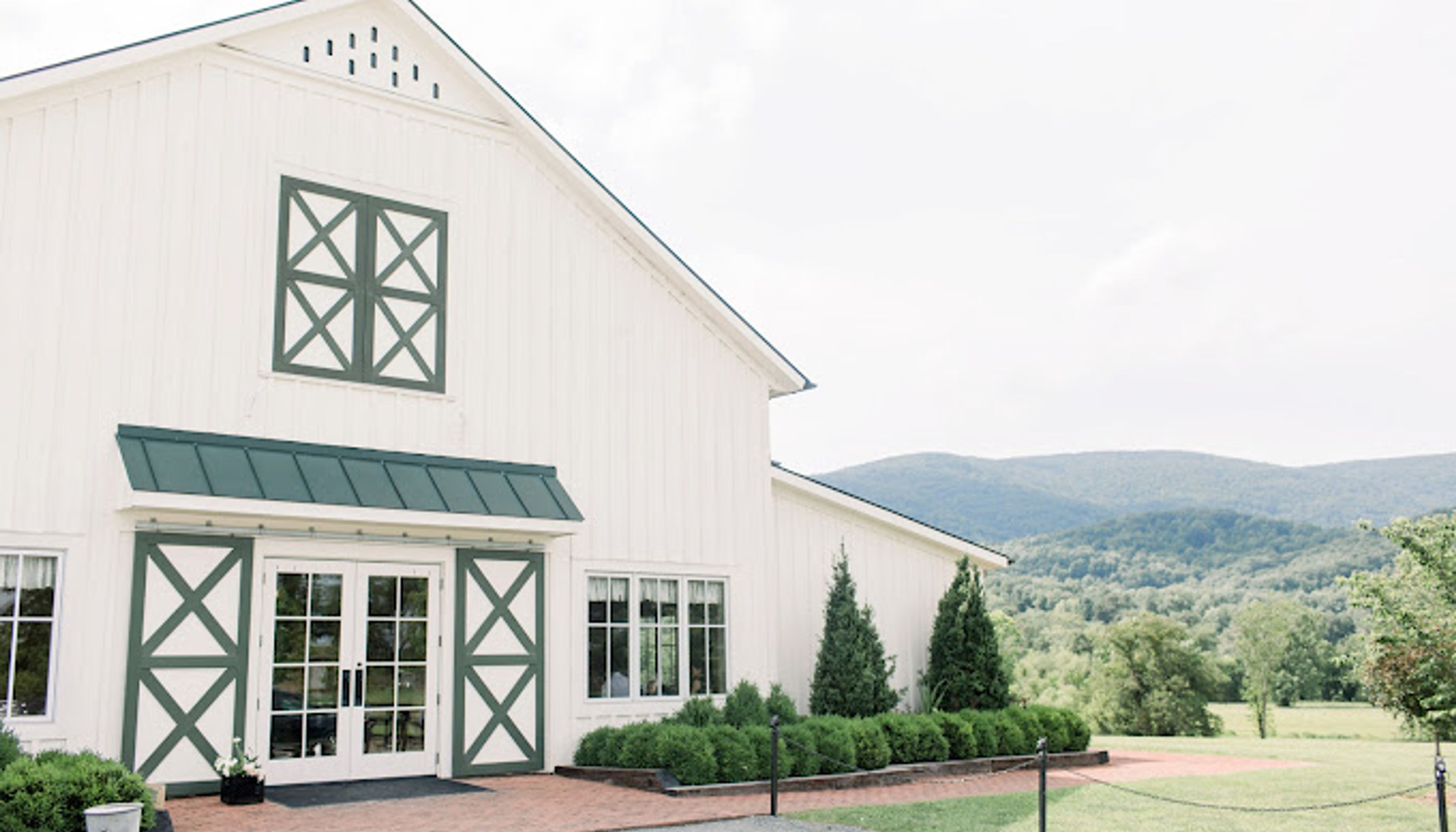 white building with green trip in front of mountain range